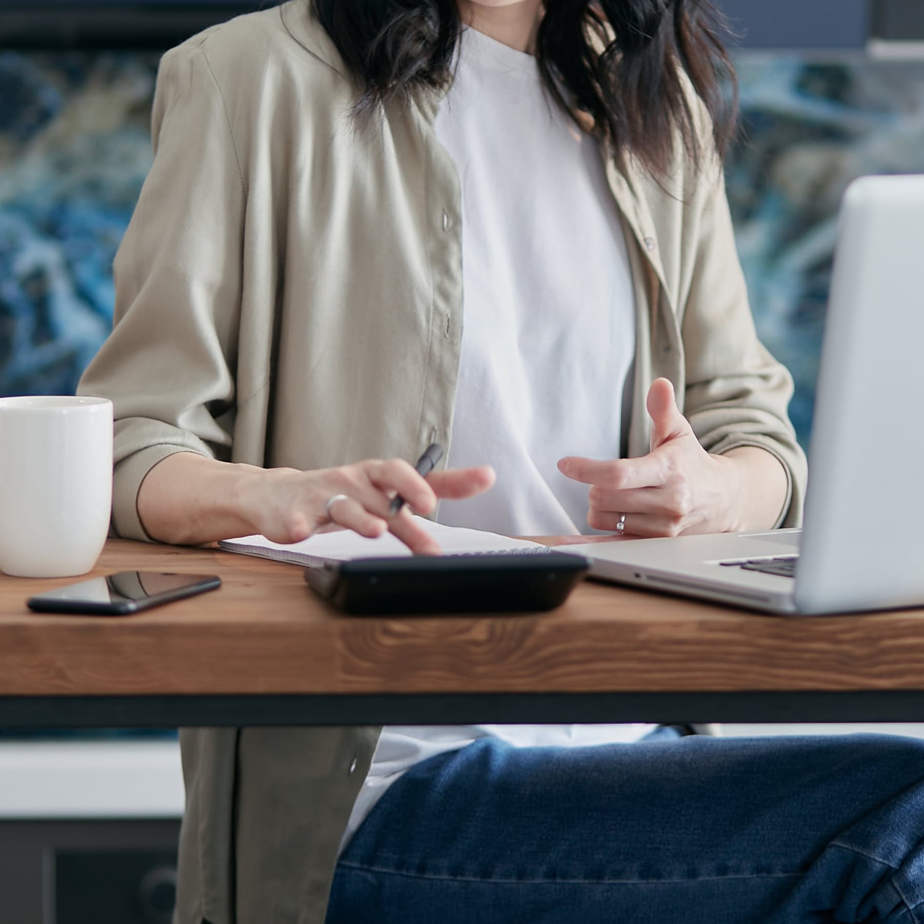 person sitting at a table with a calculator and laptop